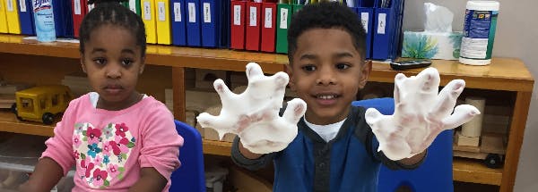 Two children, one holding up hands covered in white material