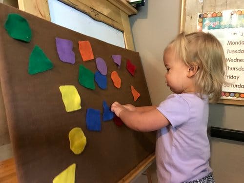 Child playing with felt shapes on an easel