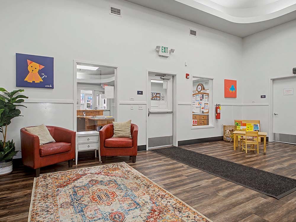 Lobby with two red chairs, a rug, and a child-sized table and chairs