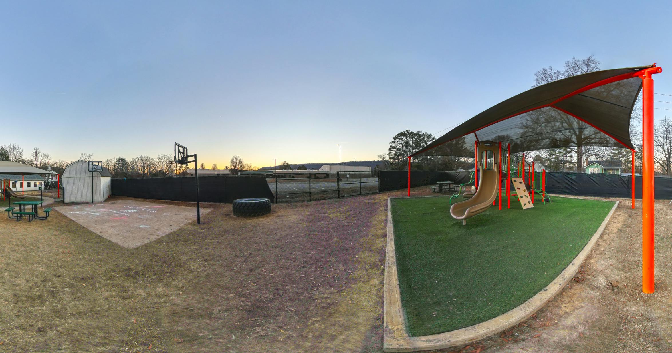 Playground with a slide, climbing wall, picnic table, and basketball hoop