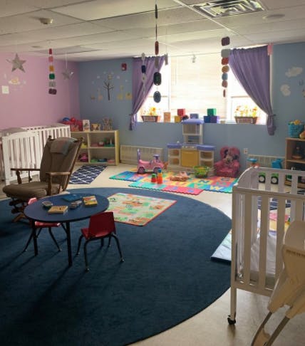 Nursery room with cribs, small tables, and play mats