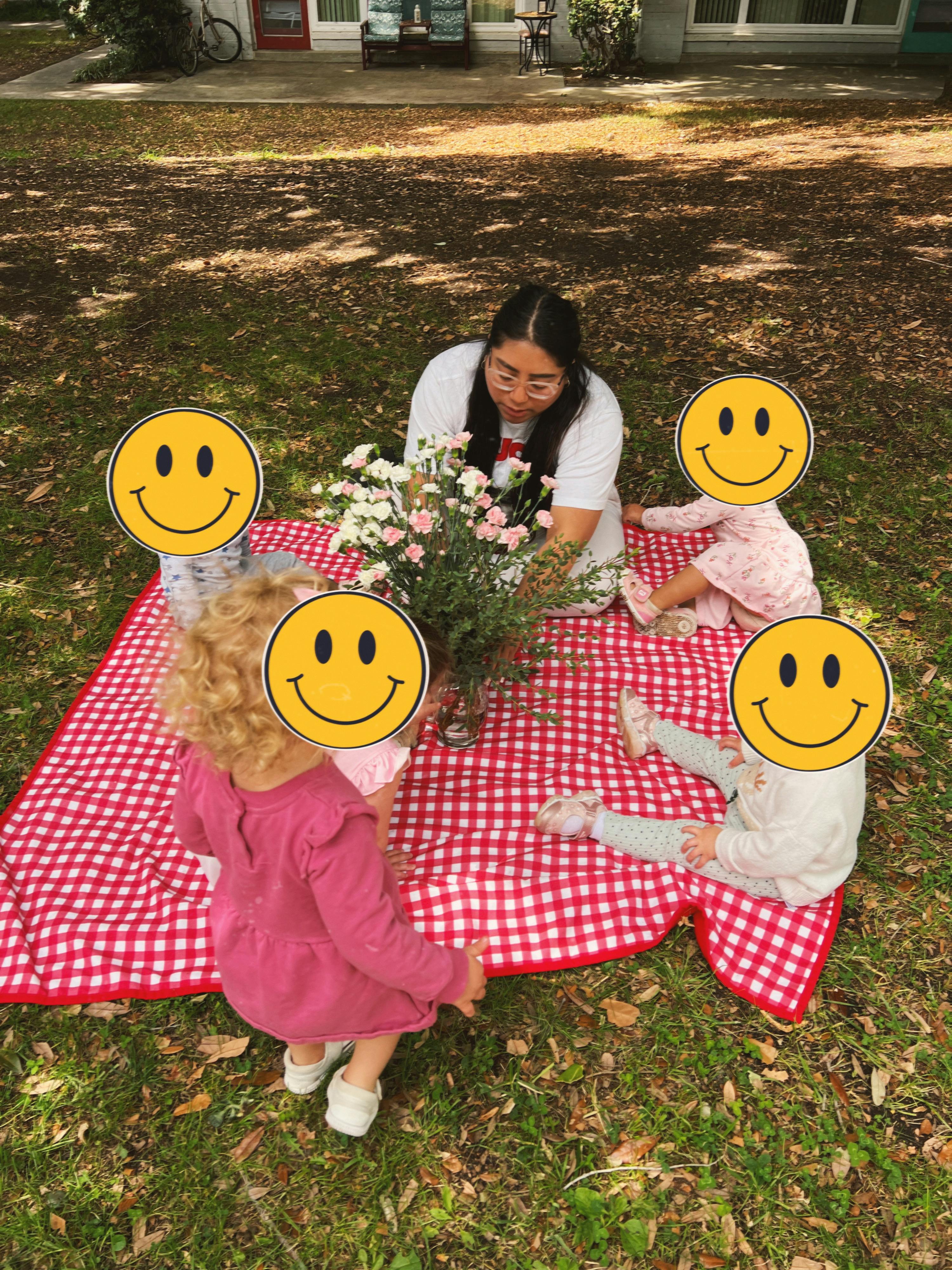 Person and children on a red and white checkered picnic blanket