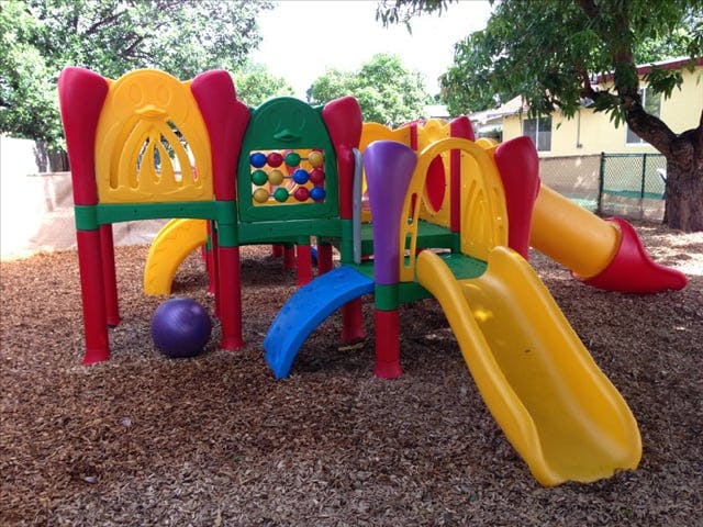Colorful playground structure with slides and a purple ball on wood chips