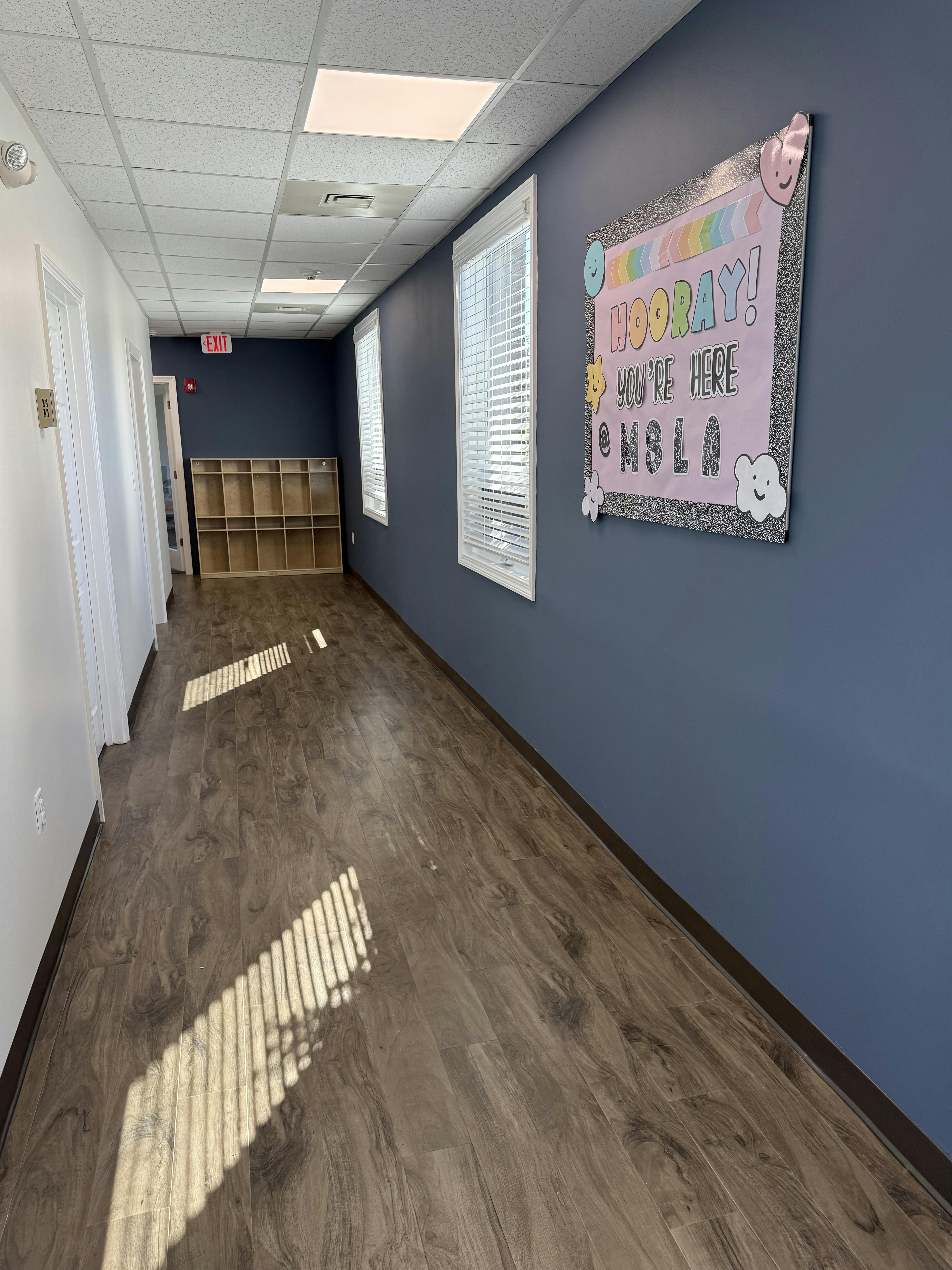 Hallway with blue walls, windows, and a bulletin board