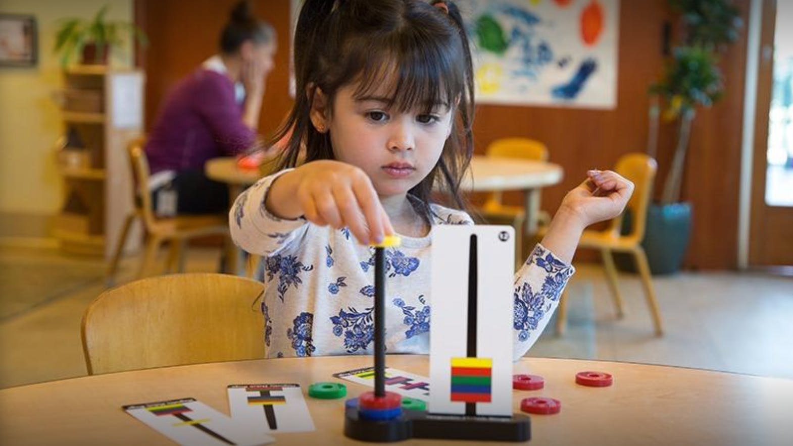 Child playing with a stacking toy at a table