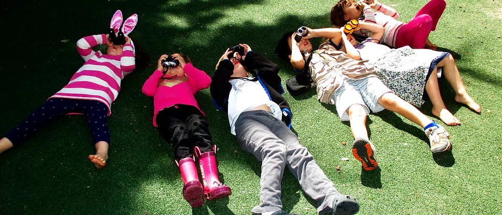 Five children lying on grass looking up