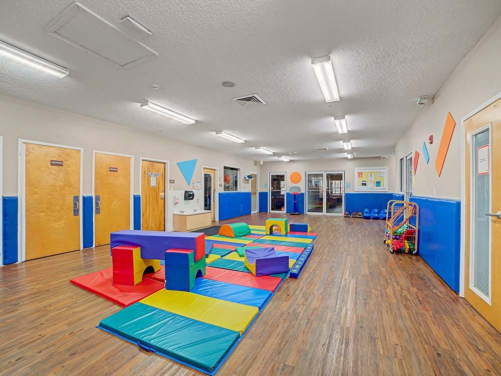 Indoor play area with colorful soft play equipment on mats