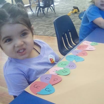 Child at a table with colorful paper shapes