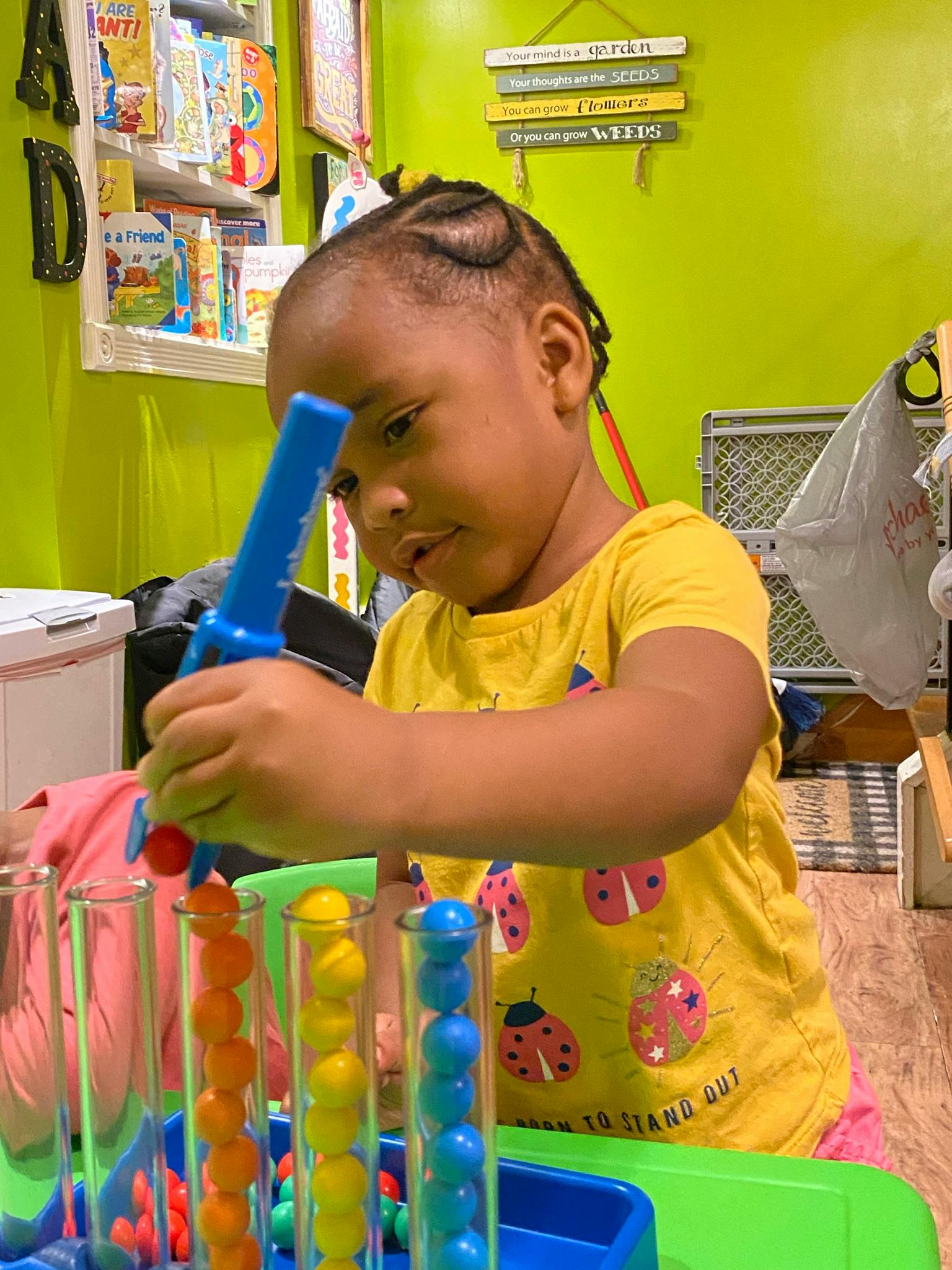 Child playing with a toy that sorts colorful balls into clear tubes