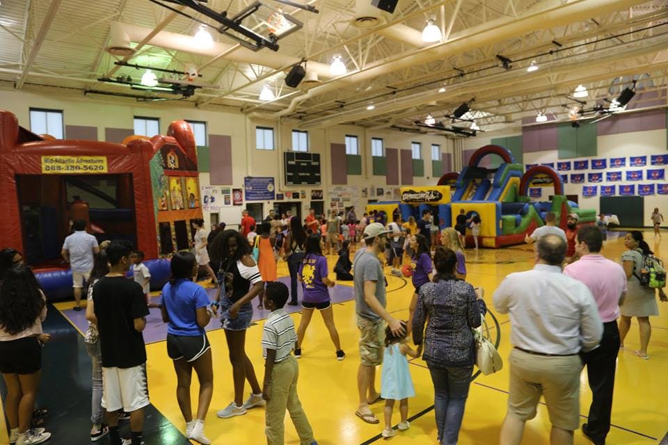 People gathered in a gymnasium with inflatable bounce houses