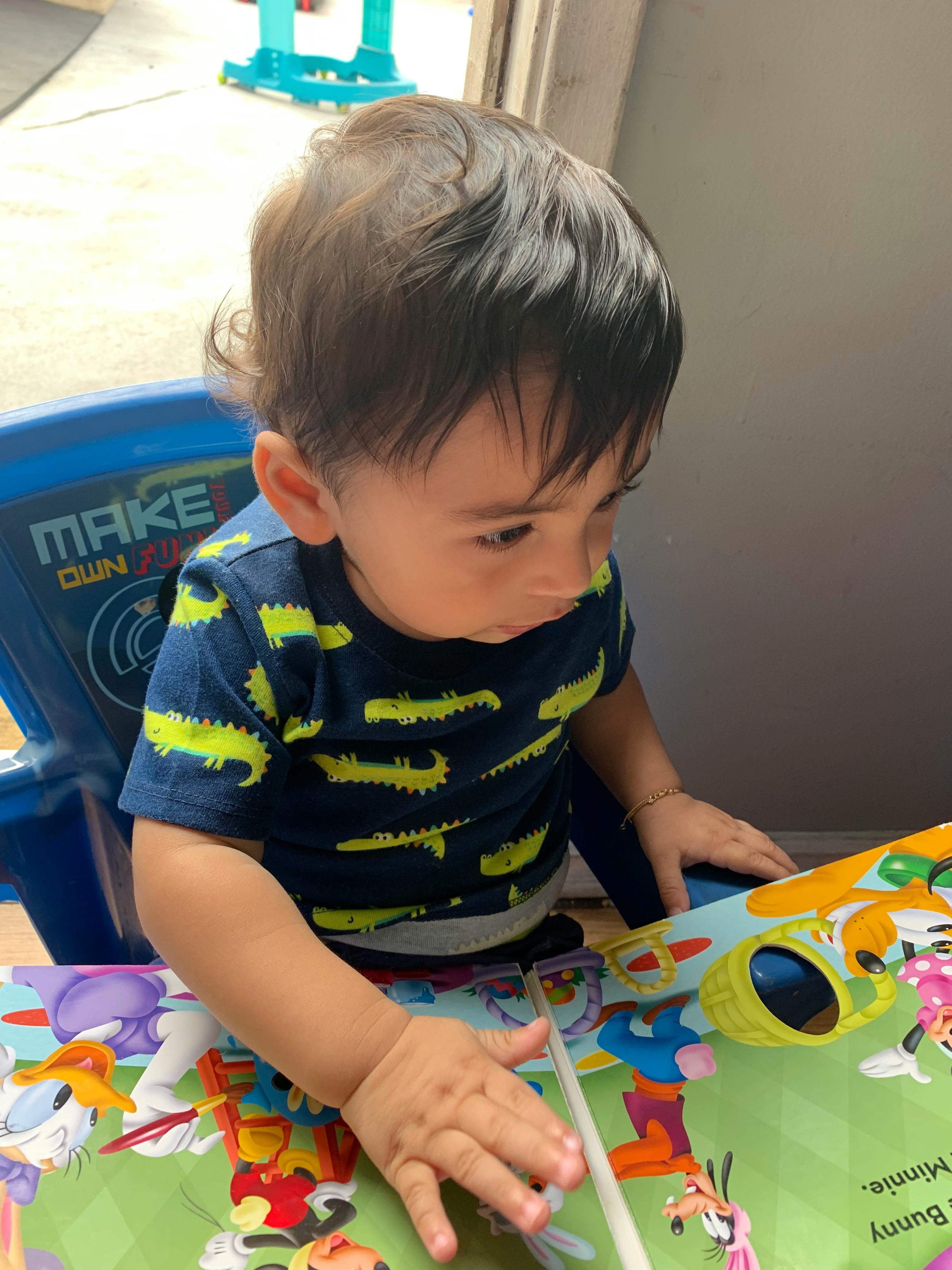 Child in a high chair looking at a colorful book