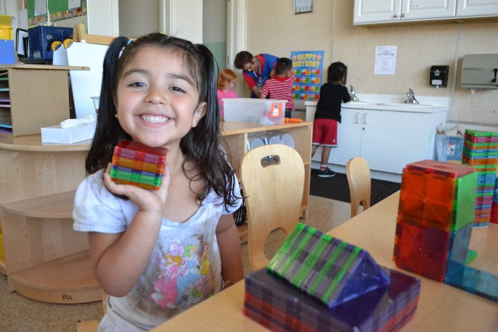 Child holding colorful blocks in a classroom