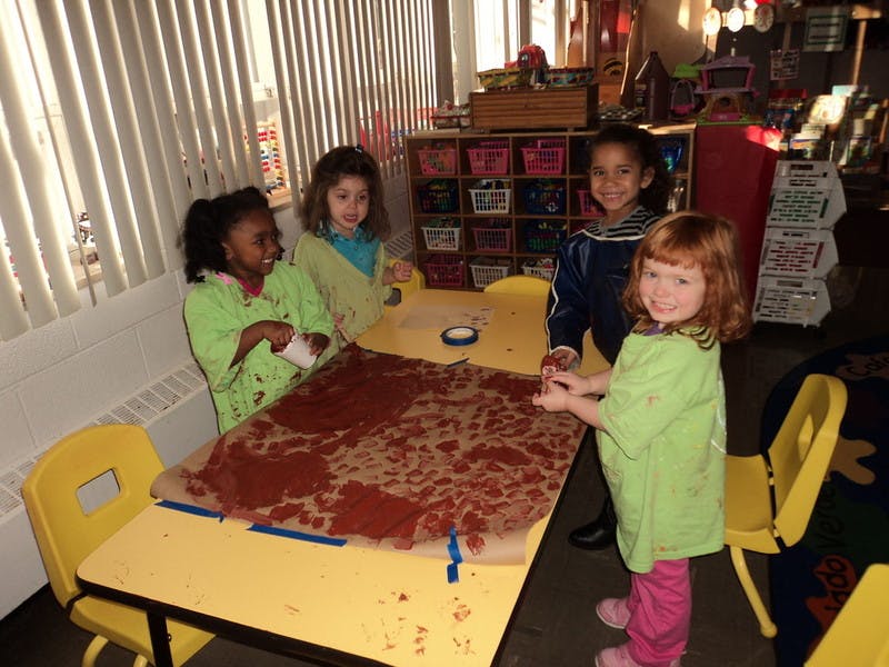 Four children standing around a table with a brown textured surface