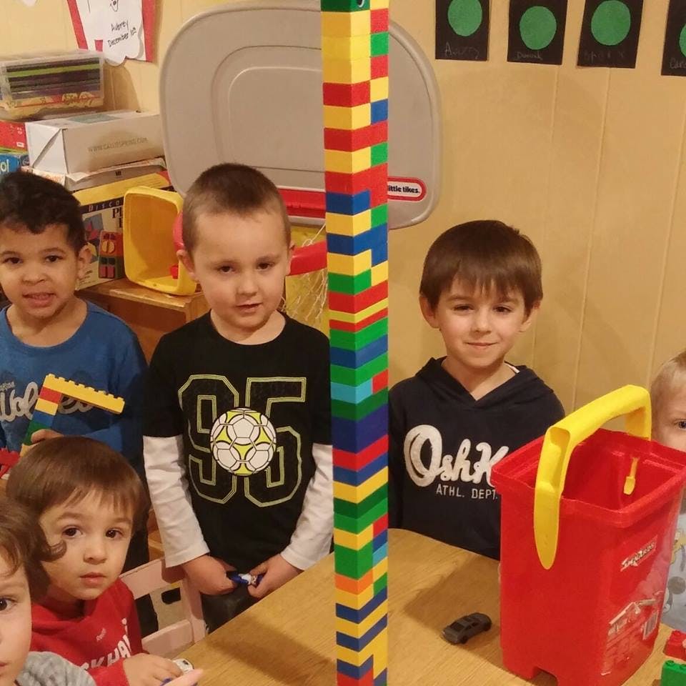 Children standing around a tall tower of colorful building blocks