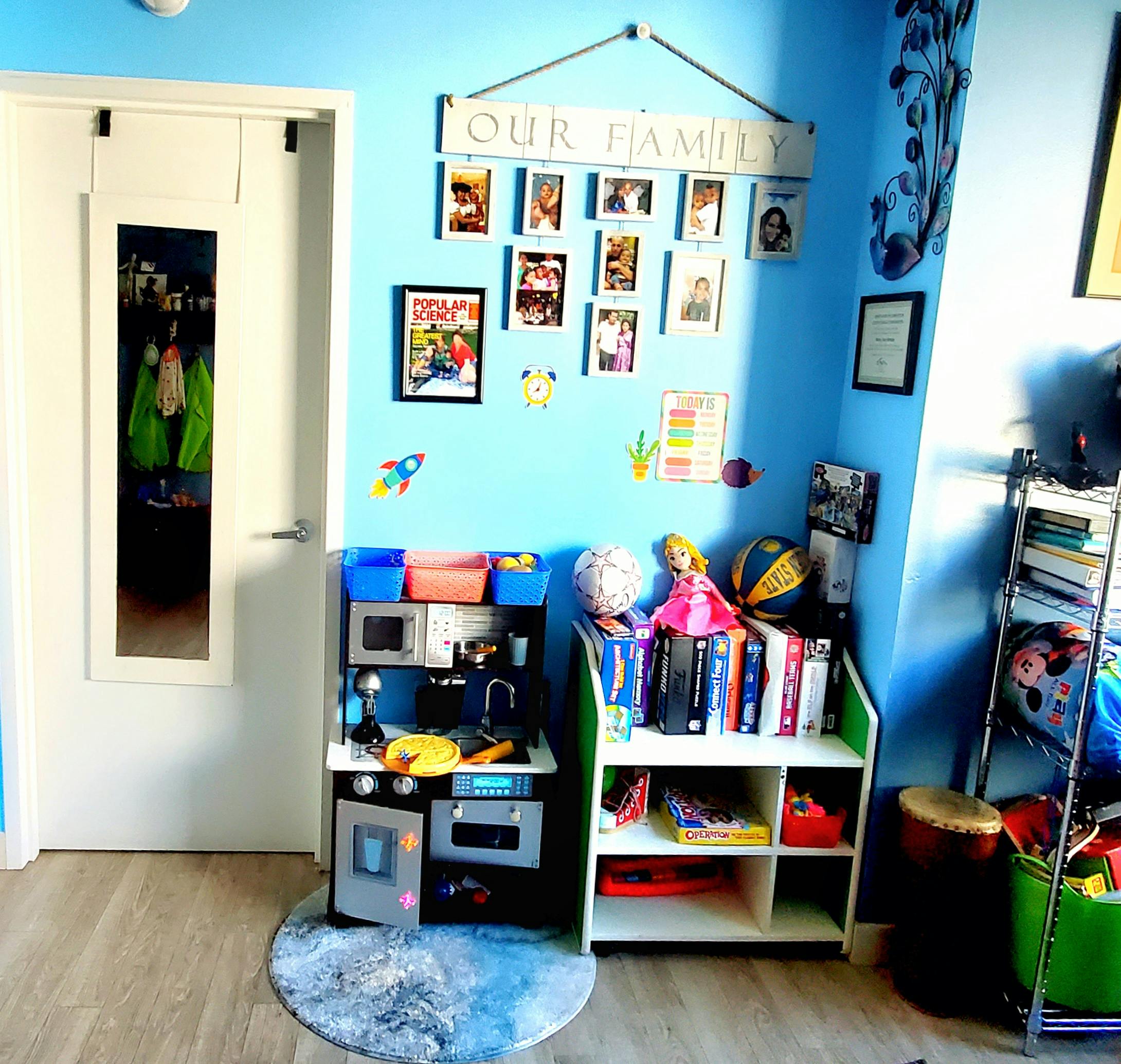 Play kitchen and bookshelf in a room with blue walls and family photos
