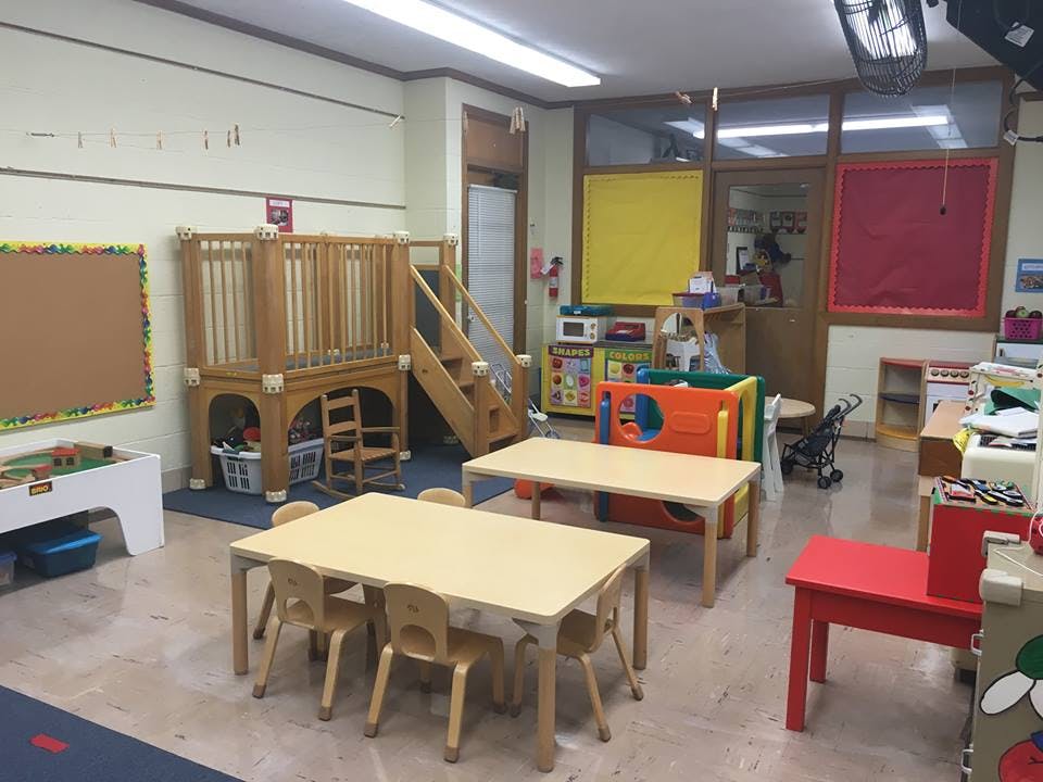 Playroom with small tables and chairs, and a wooden play structure