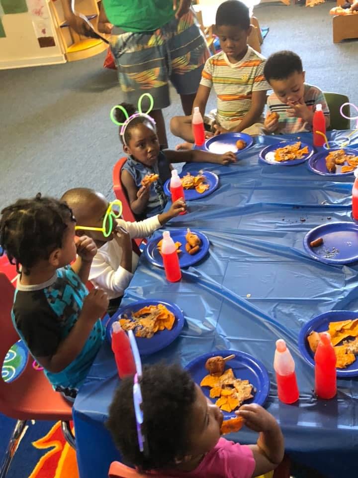 Children eating snacks at a table with blue plates and red bottles