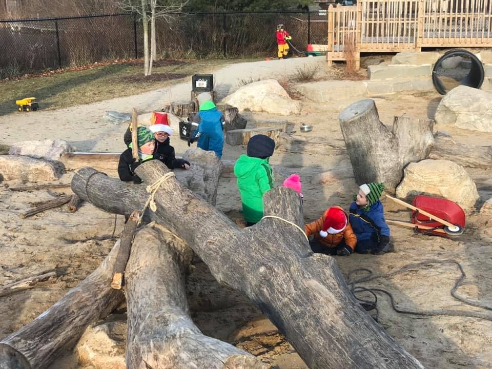 Children playing outdoors with logs and sand