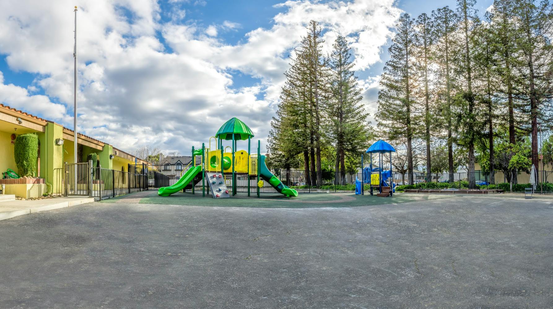 Playground equipment on a paved area with trees in the background