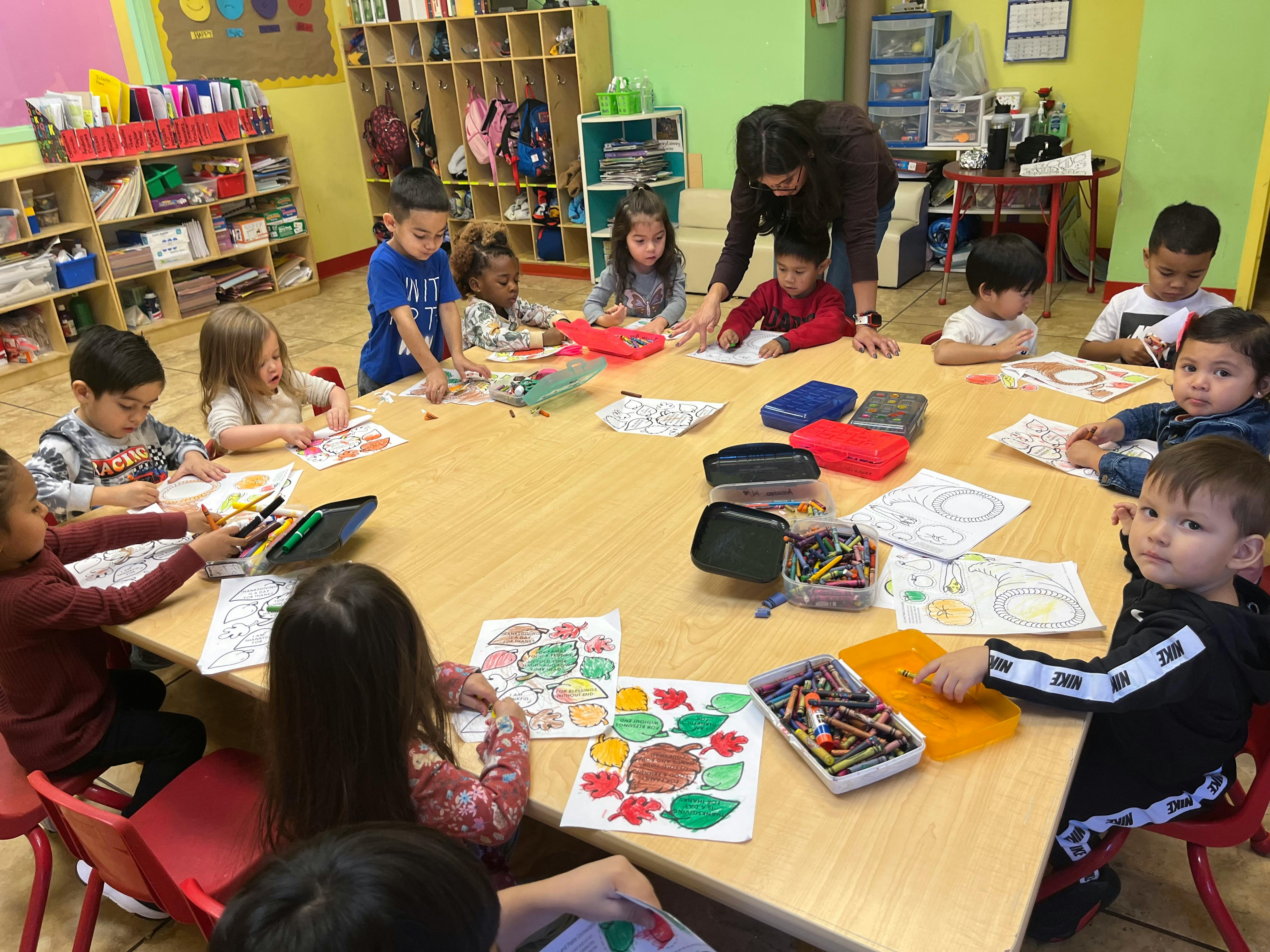 Adult and children gathered around a table doing crafts in-class activities