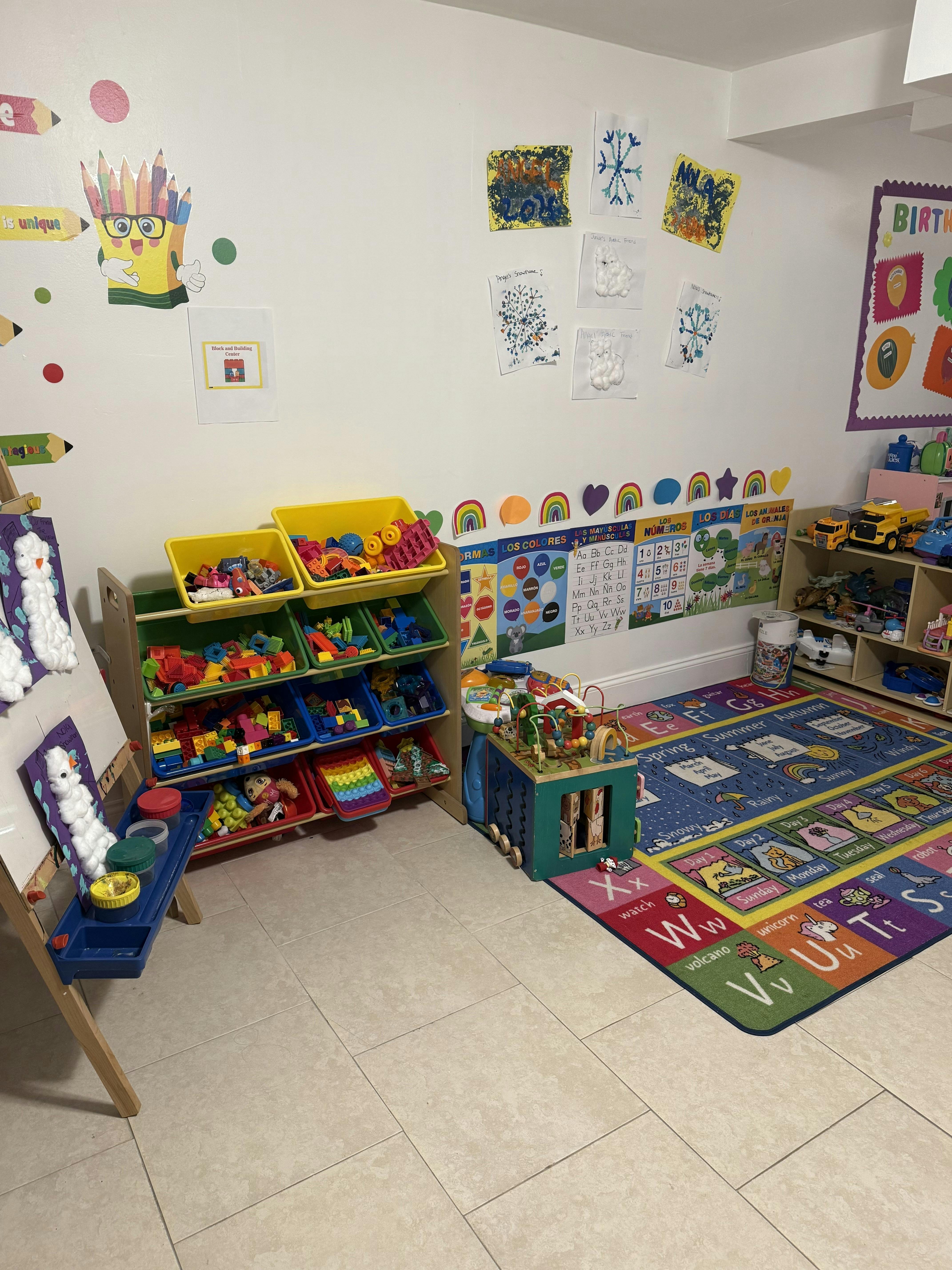 A colorful classroom with art on the walls, toy storage shelves, and a large alphabet rug