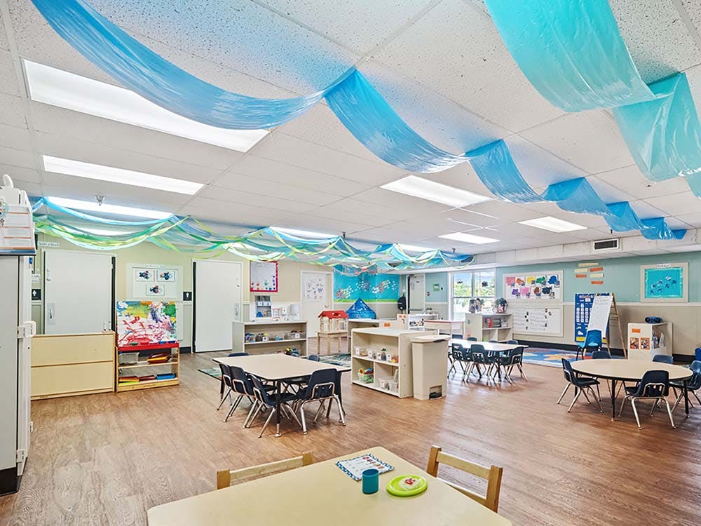 Empty colorful children's classroom with tables and chairs