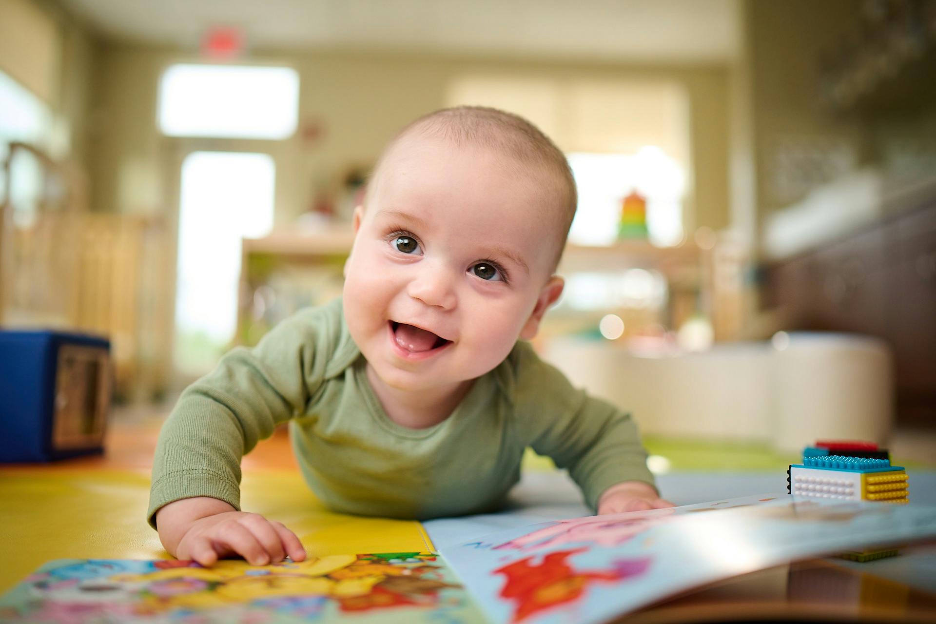 Baby on stomach looking up from open book