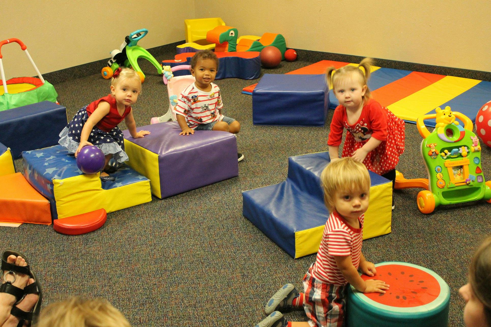Children playing on soft blocks and toys in a room