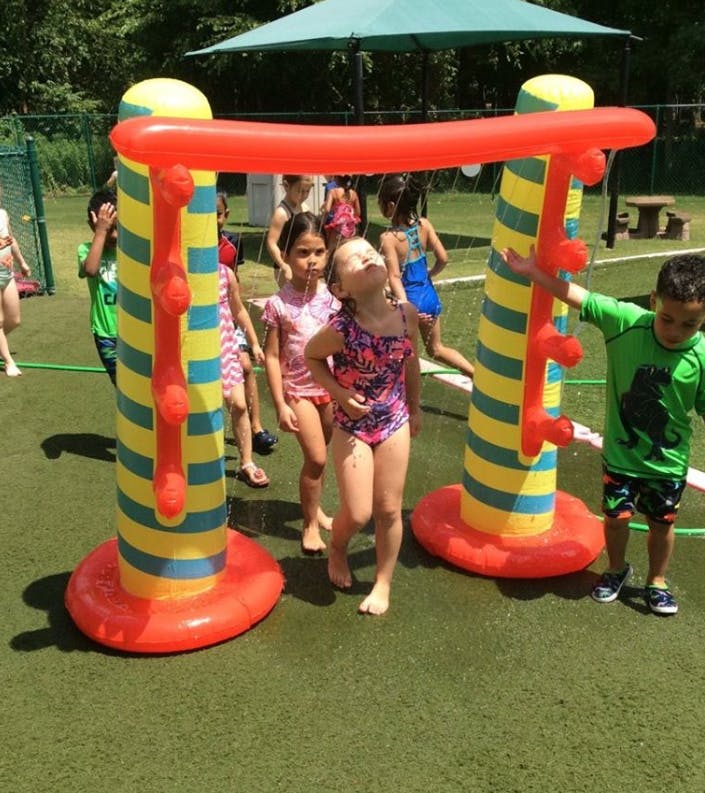 Children playing with an inflatable water toy outdoors