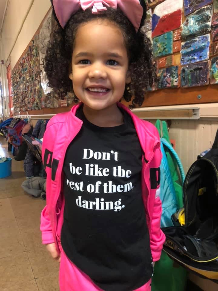 Child wearing a pink jacket and a black shirt with text