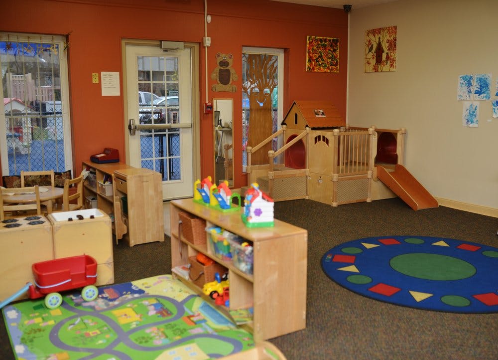 Indoor play area with wooden structures, toys, and colorful rugs