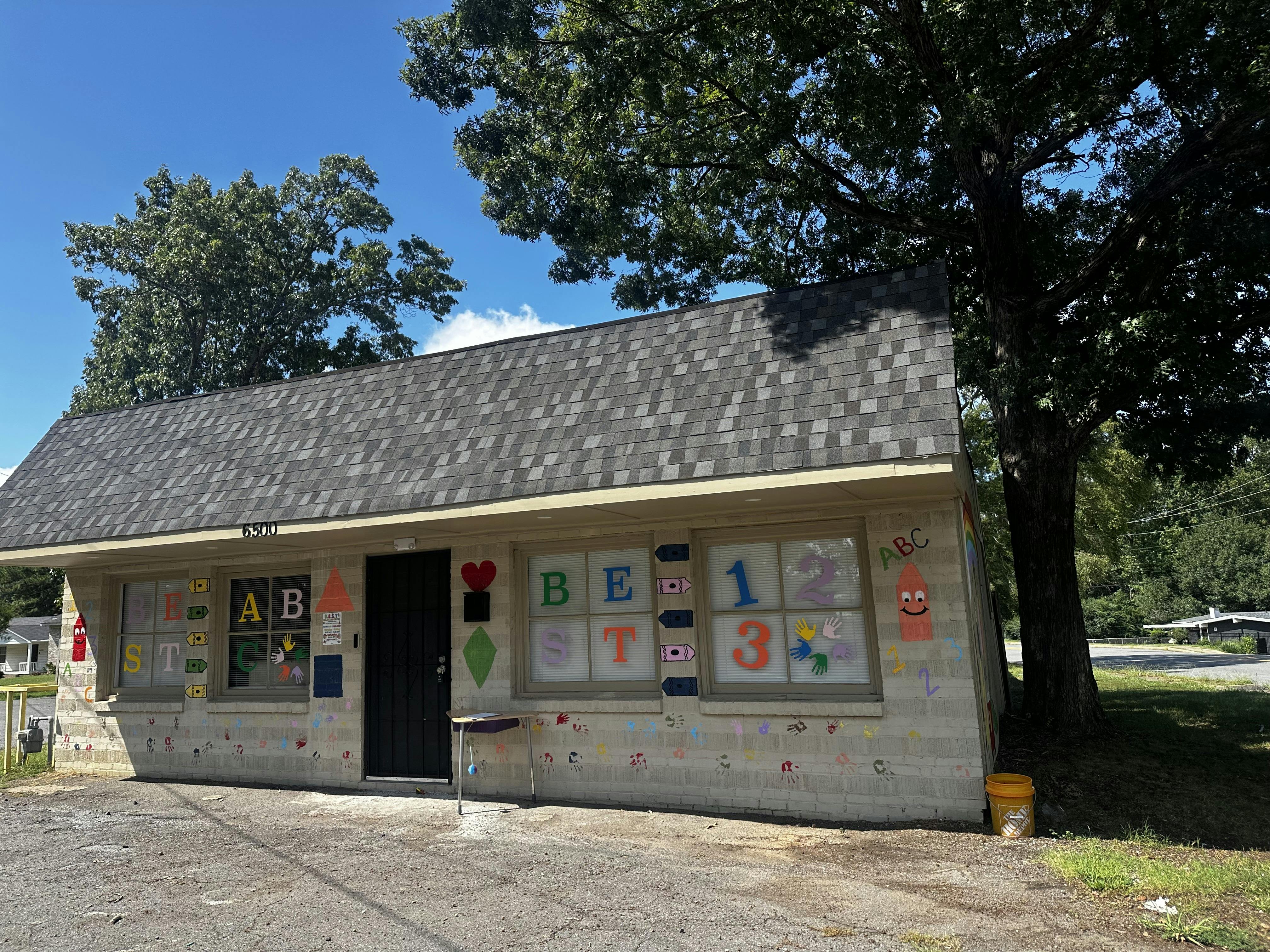 Small building with a dark door and windows decorated with letters and numbers