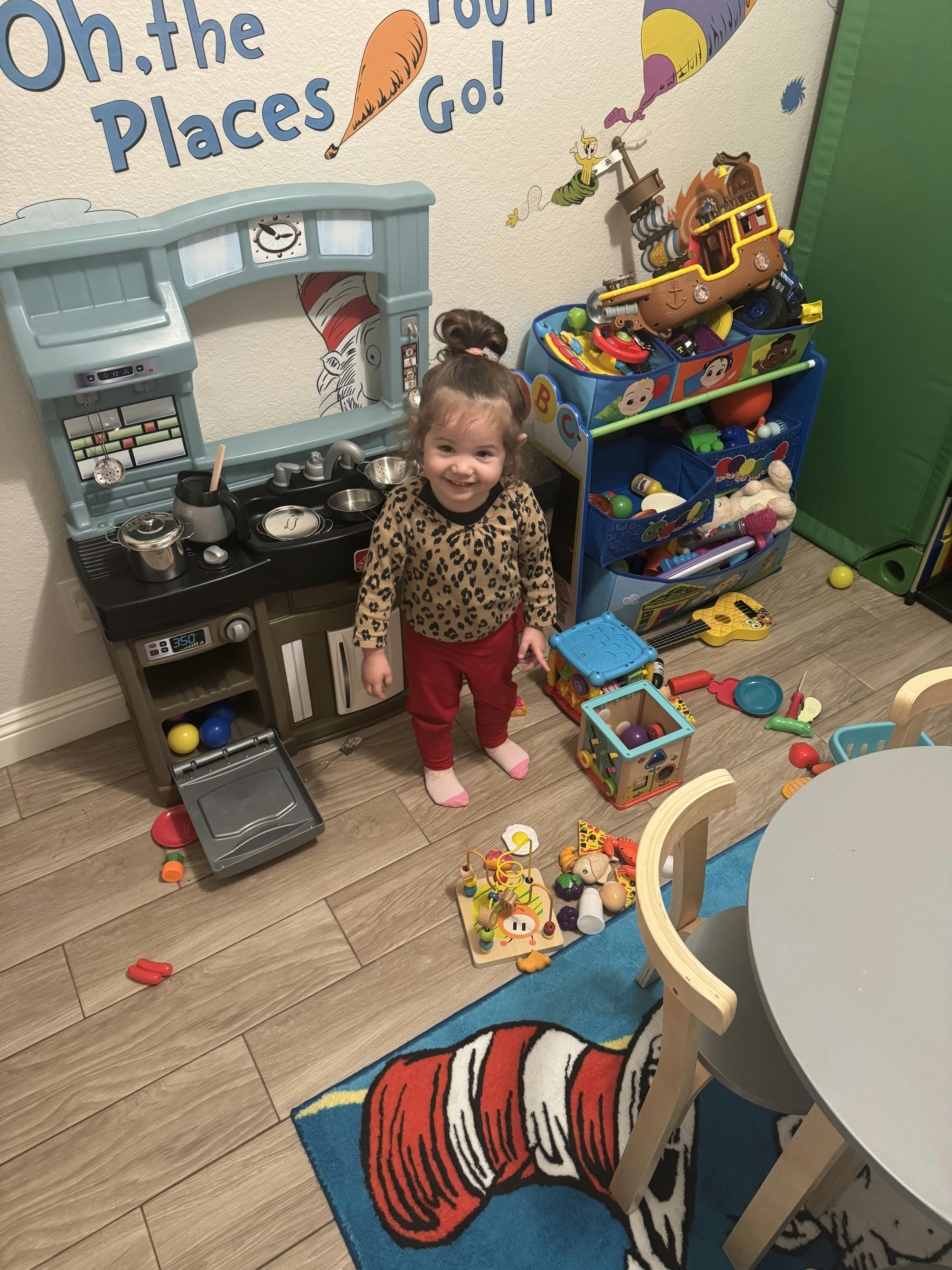Smiling child standing next to a play kitchen