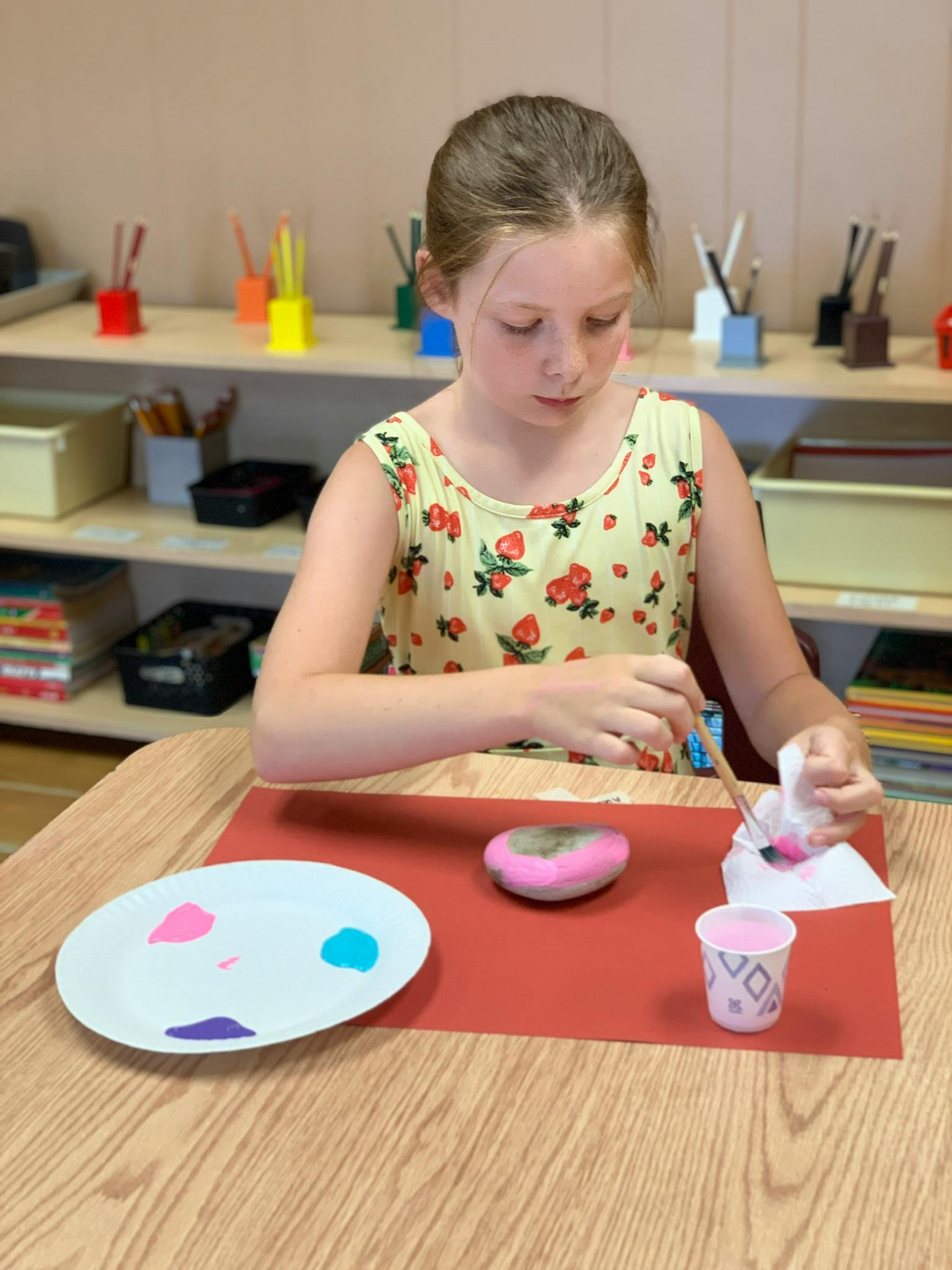Child painting a rock at a table