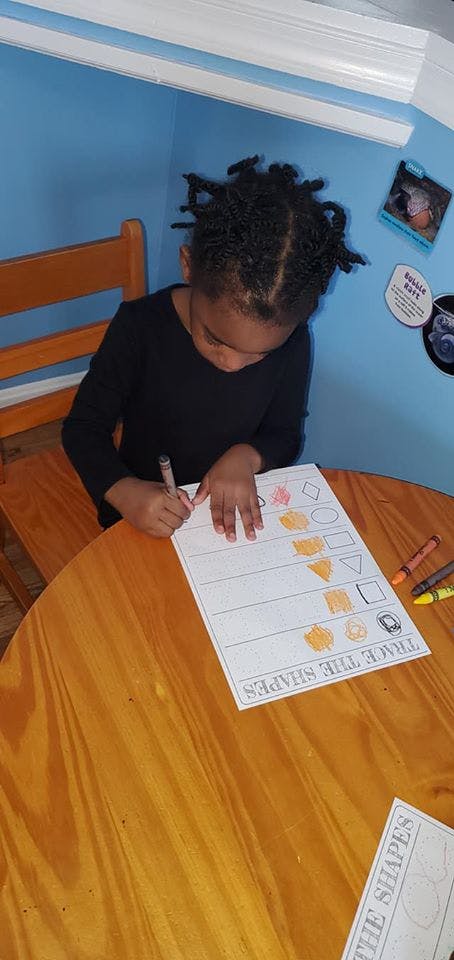 Child tracing shapes on a worksheet at a table