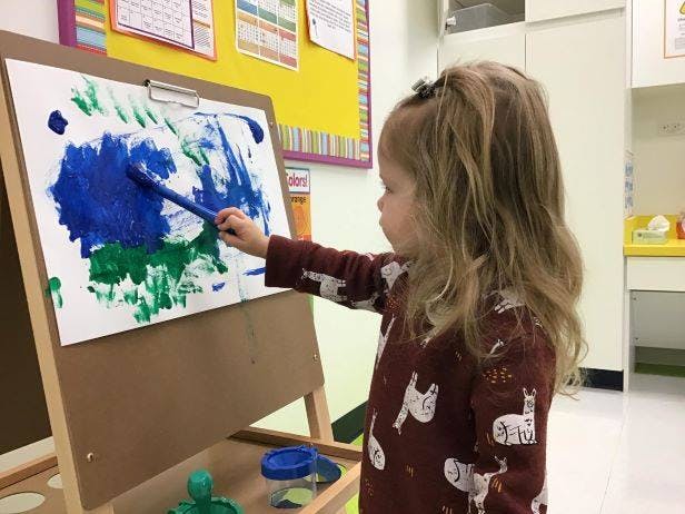 Child painting on an easel in a classroom