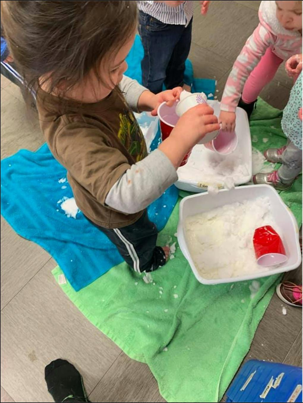 Child pouring white powder from one cup to another