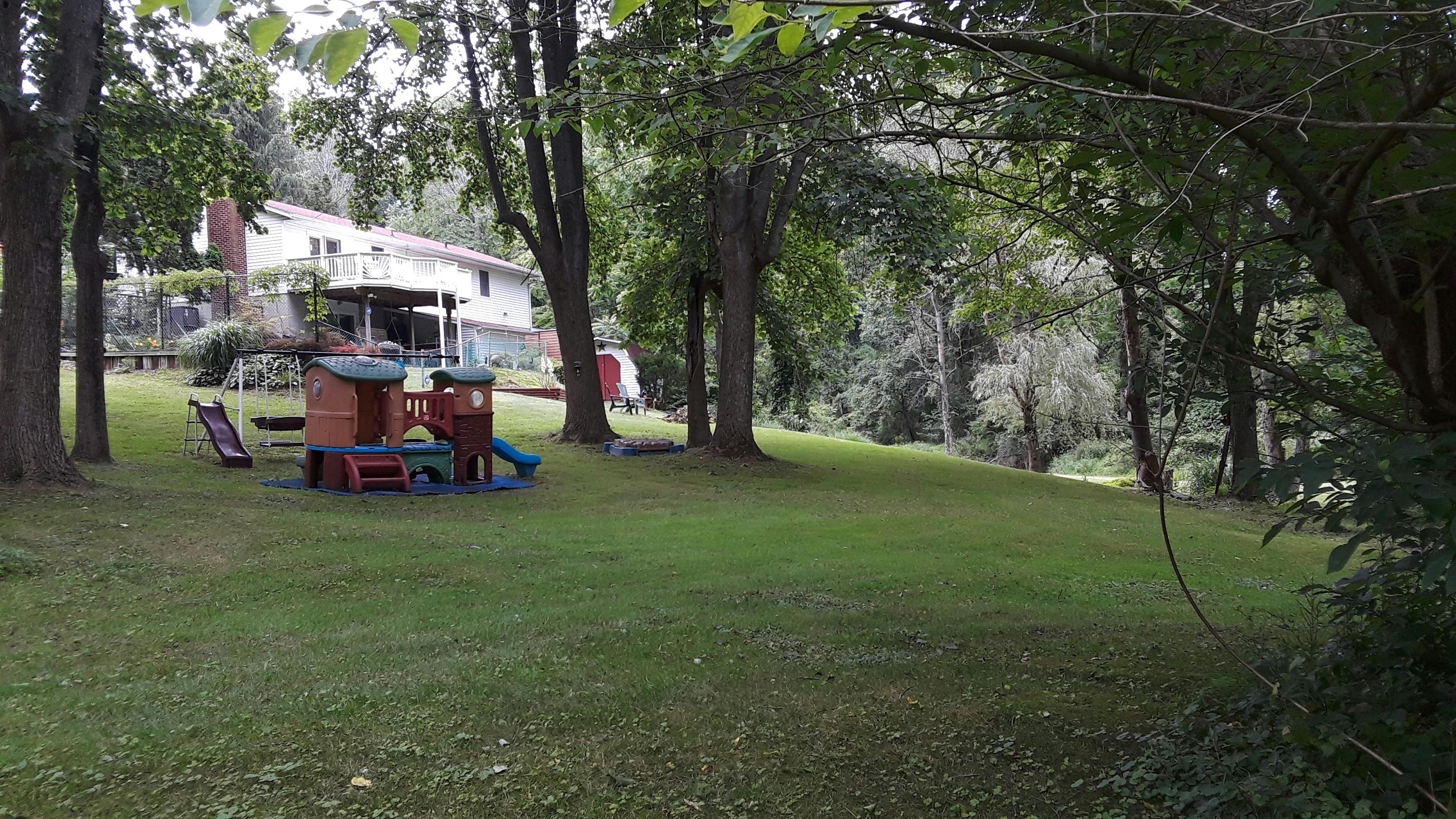 Plastic play structure and slide in a grassy backyard near a house
