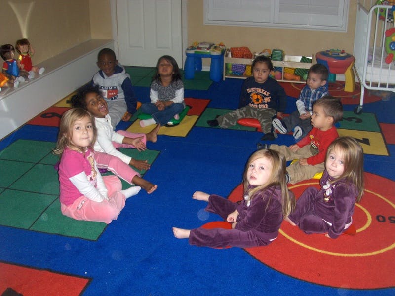 Group of children sitting on colorful mats in a room