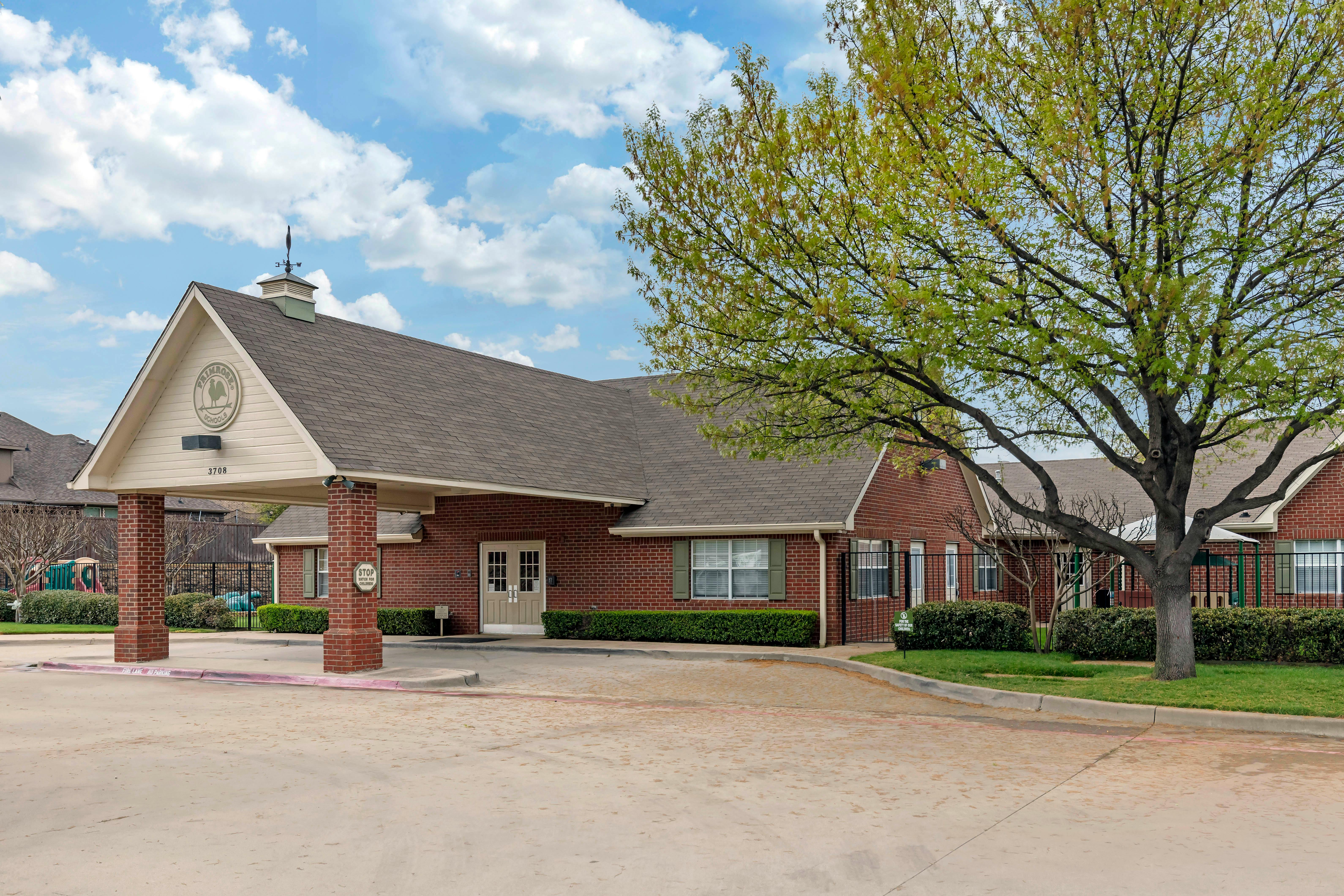 Brick building entrance with an overhang, number 3708, and a large green tree