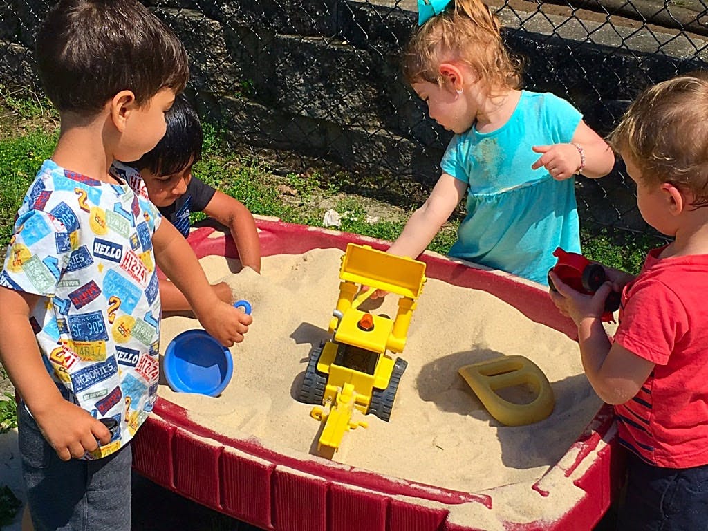 Children playing in a sandbox with toys