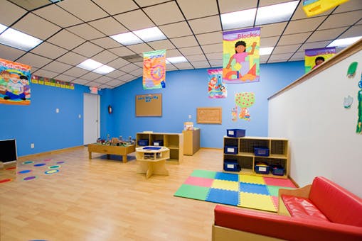 Empty classroom with blue walls, wooden floor, and colorful mats