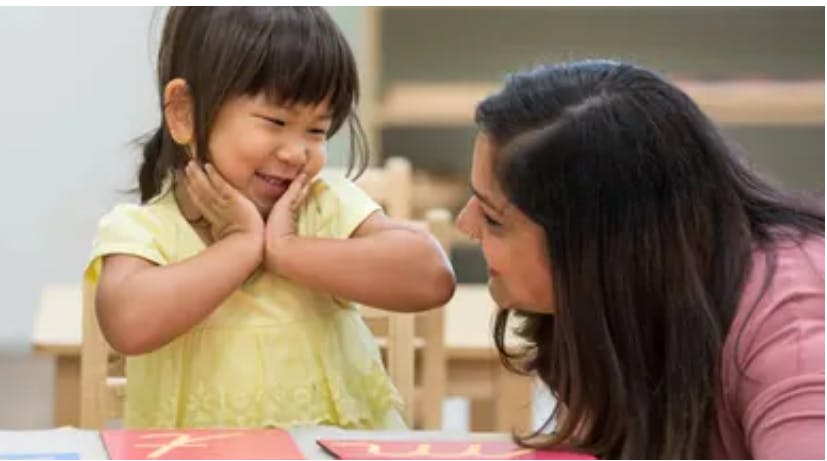 Child with hands on face looking at person