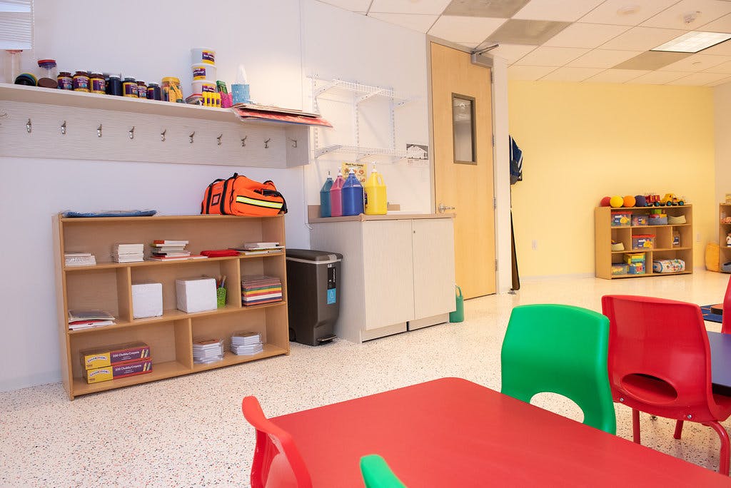 Classroom with small red tables and green and red chairs