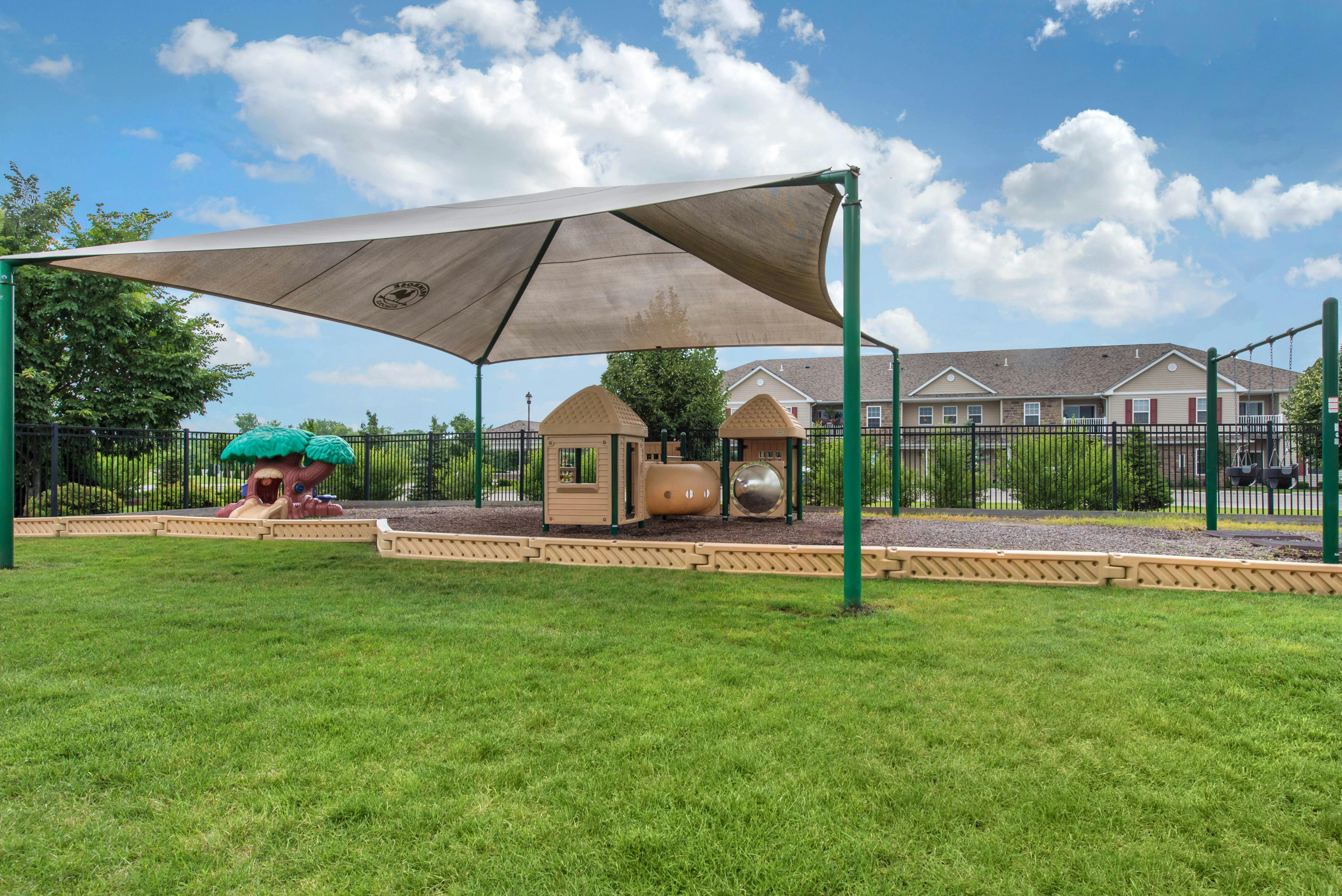 Playground with swings, play structure, and green grass