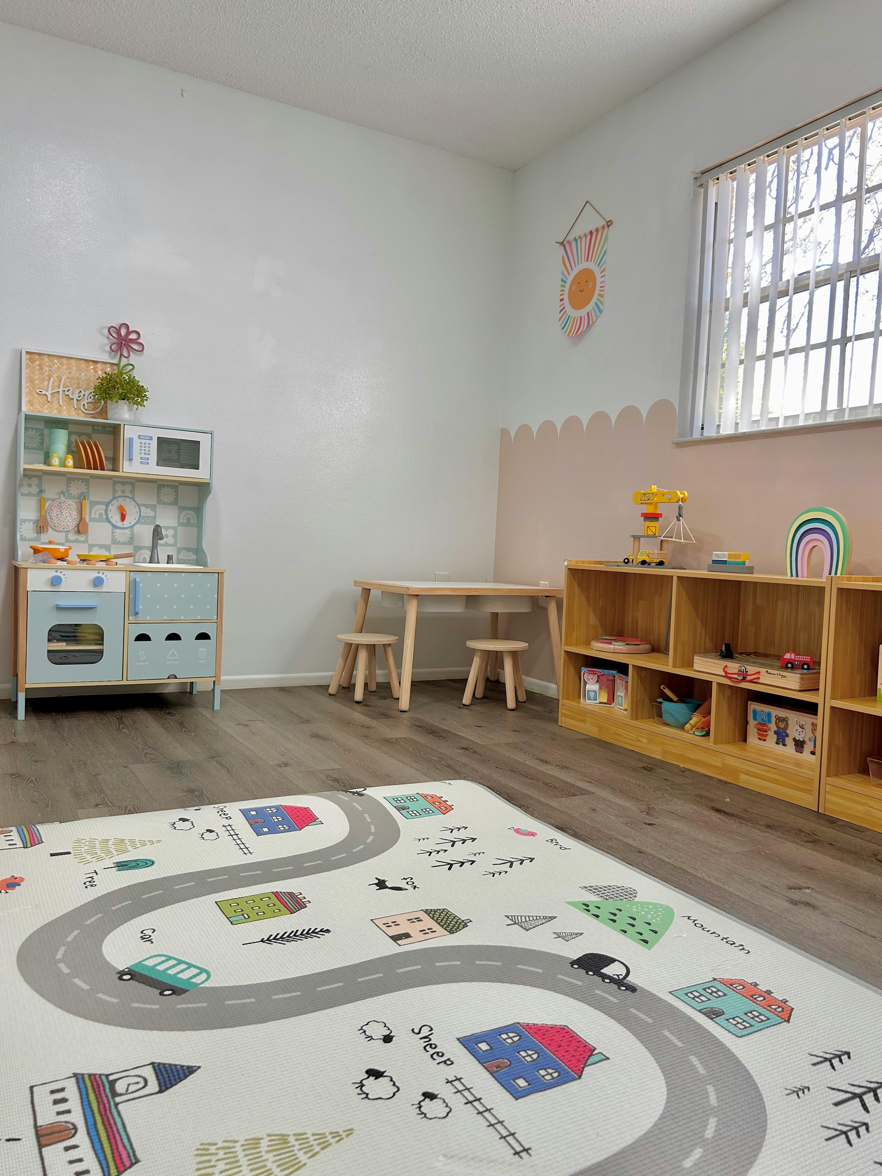 Playroom with toy kitchen, small table and chairs, and a road map rug