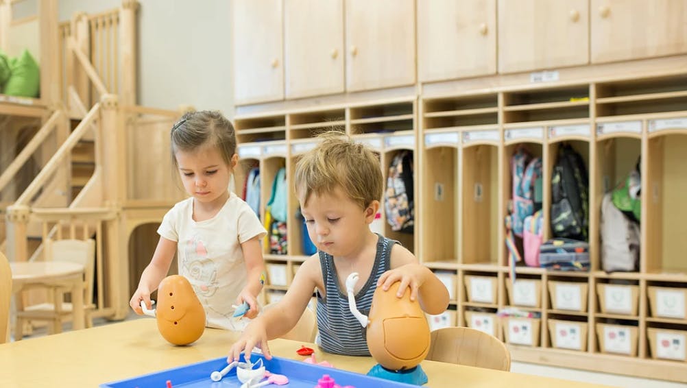 Two children playing with toys at a table in a classroom