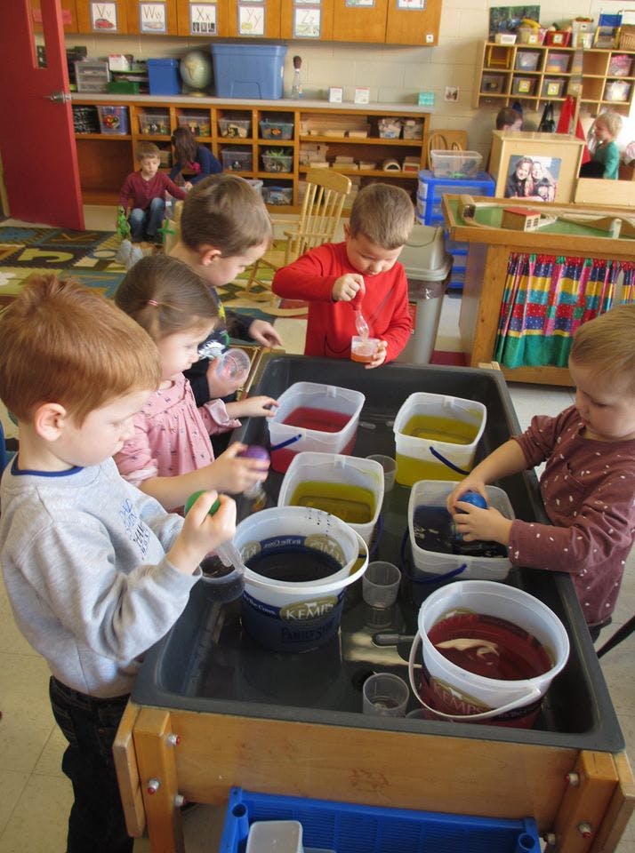 Children playing with colored liquids in a classroom