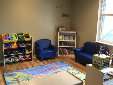 Children's play area with toy storage, small chairs, and a bookshelf