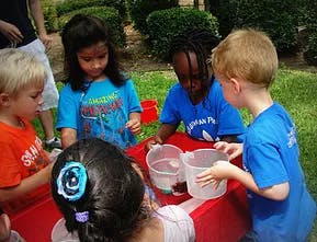 Children gathered around a table with plastic containers
